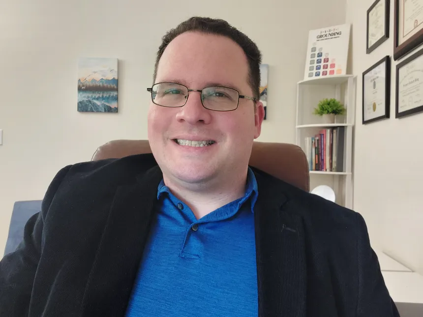 Greg Bing, MA, LPC, smiling in his counseling office, ready for an individual online session