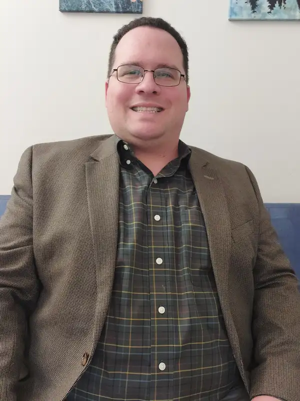 Greg Bing, Licensed Professional Counselor, smiling in a tweed jacket in his counseling office in Somerset, New Jersey